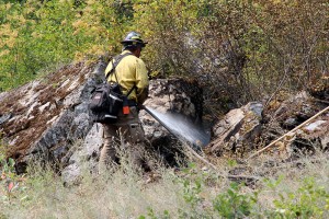 A firefighter sprays down a hot spot near the western slope of the fire line. Photo by Ben Olson.