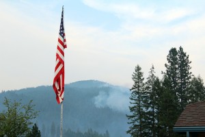 The American flag flies over the Bayview Community Center as smoke from the Cape Horn fire billows in the background. Photo by Ben Olson