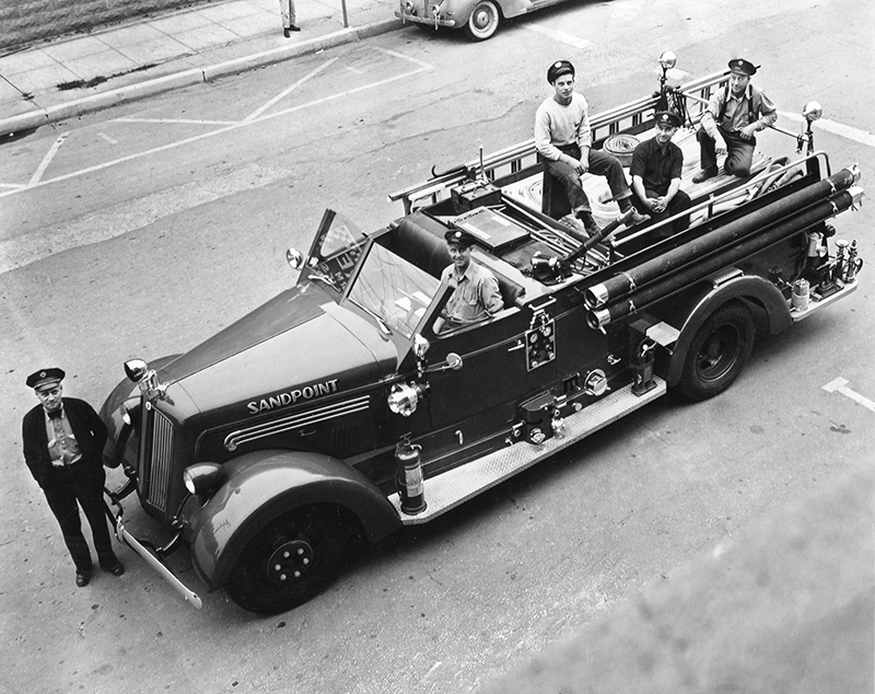The original photo, taken sometime in the late 1940s. From left to right: Claude Simon, Chief; Earl Thomas, Capt.; Earl Pitts, Capt.; Harvey Bailey, Frank Pitts. The photo was taken from the second story window of the old fire station on the corner of Second and Church. The engine was parked on Second Ave. for the photo.