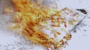 One of Craig Cobb’s signs burns in the snow. Photo by Michael Beach Nichols.