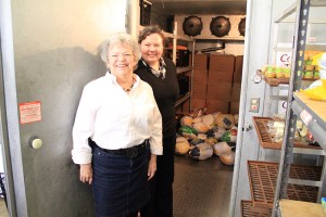 Alice Wallace, left, and Debbie Love, right, stand before a walk-in freezer that holds donated turkeys. Photo by Ben Olson.