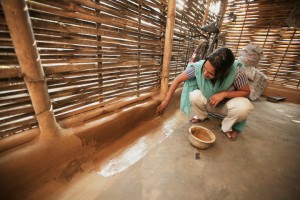 A woman coats her wall in dung to keep insects out at a Bhutanese refugee camp.
