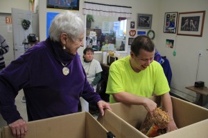Lois Miller, left, visits with PSNI participant Dewey Horowitz, right, as he fills bags with wood chips. Photo by Ben Olson.