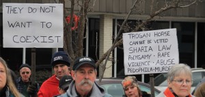 A sign announcing the "Trogan (sic) horse" worn by a woman in a "Heather Scott" hat. Photo by Ben Olson.