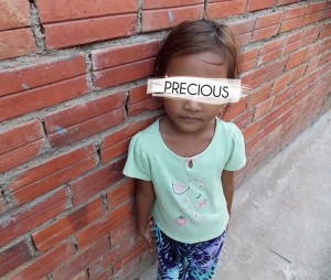 A young girl saved from human trafficking poses against a brick wall. Photo courtesy of Rapha House.