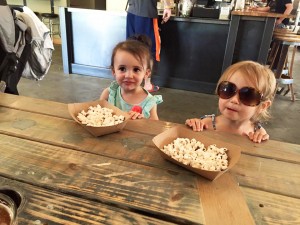 Beer for the big kids, popcorn for the small ones (left to right): Lily DeFord, 1 ½, and Lucy Thwaites, 2, kick back with some popcorn while their parents enjoy some microbrews at MickDuff’s Beer Hall. Photo by Kayle DeFord.
