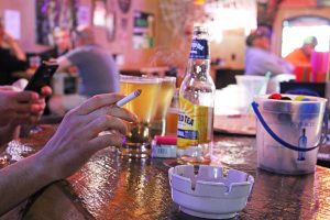 A patron at A&P’s enjoys a cigarette inside the bar. Photo by Ben Olson.