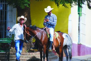 In Trinidad, Cuba, cowboys pause in a rare wifi zone to check the internet. Photo by Katie Botkin.